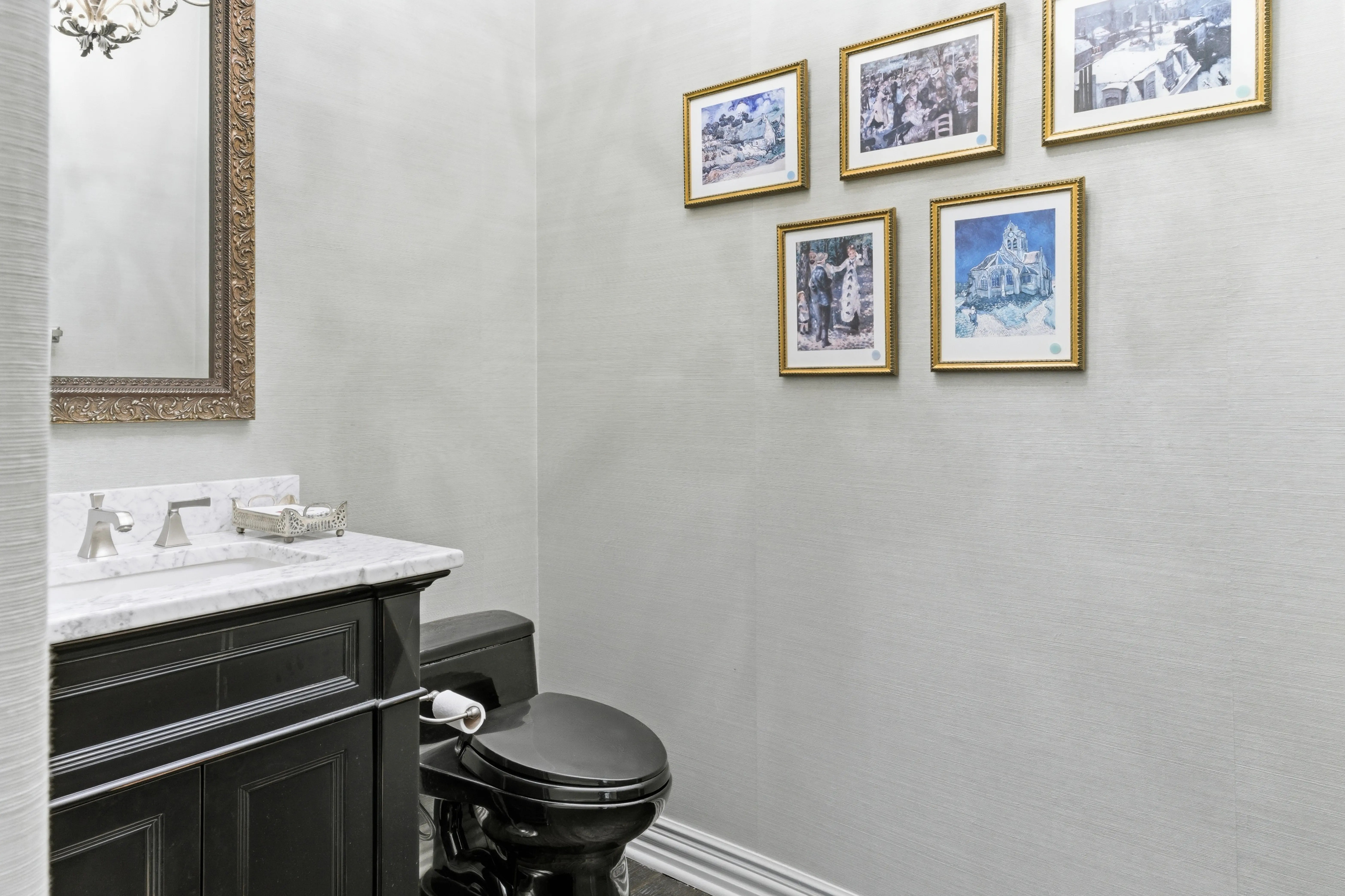 Elegant powder room with dark vanity, marble countertop, and gallery wall